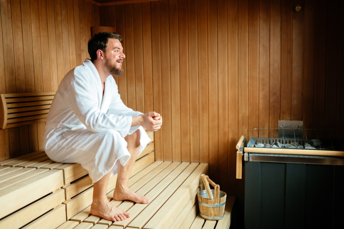 Handsome man relaxing in sauna during wellness weekend